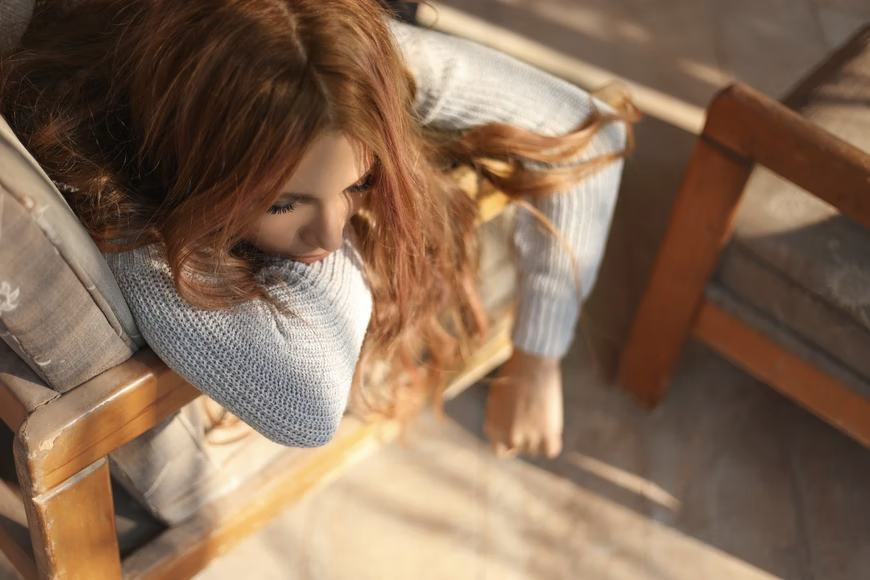 A woman is slumped over a chair, and appears to be thinking. Visual representation for dealing with obsessive thoughts in recovery from addiction.