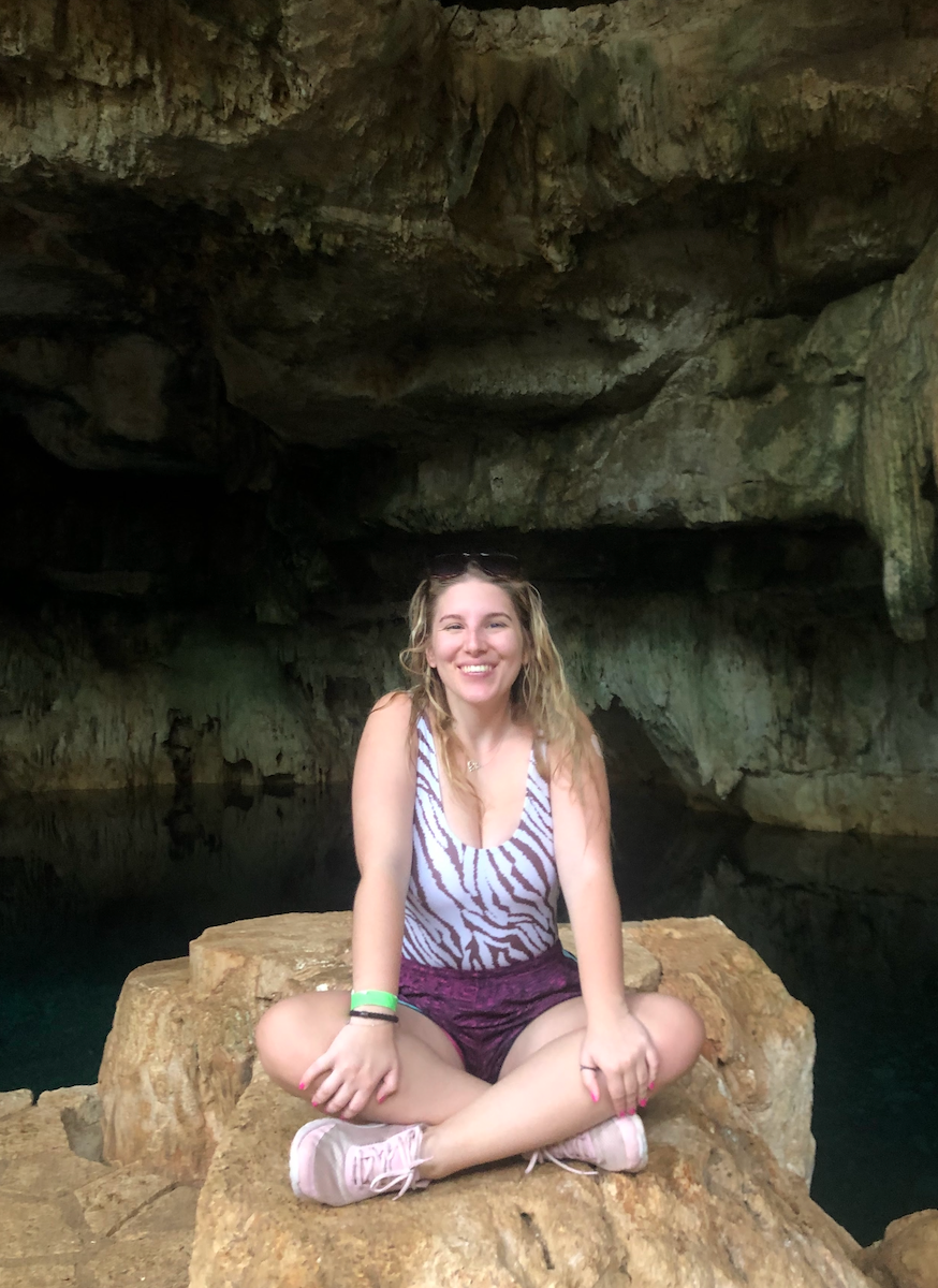 A picture of the author sitting on a rock in a cenote, an underwater cave
