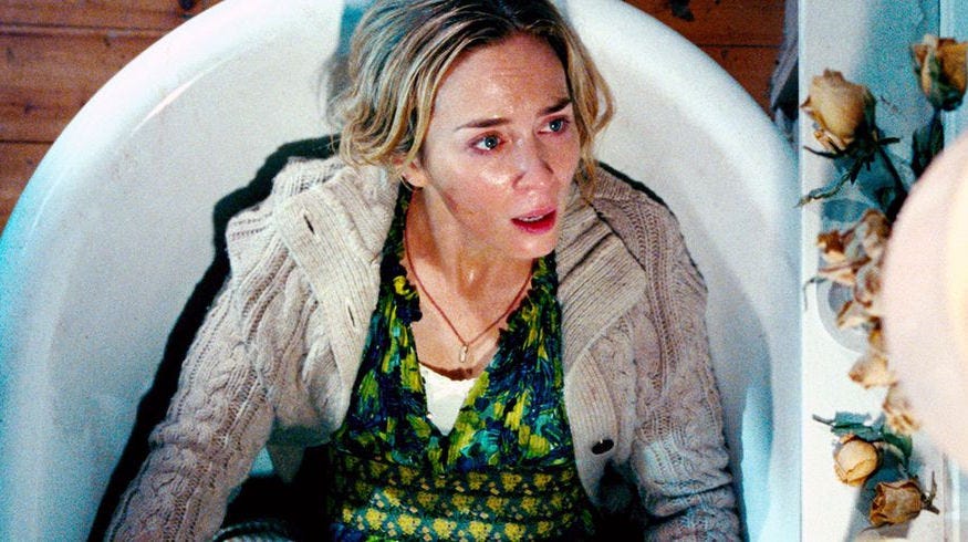 A woman lies fully clothed in a tub terrified