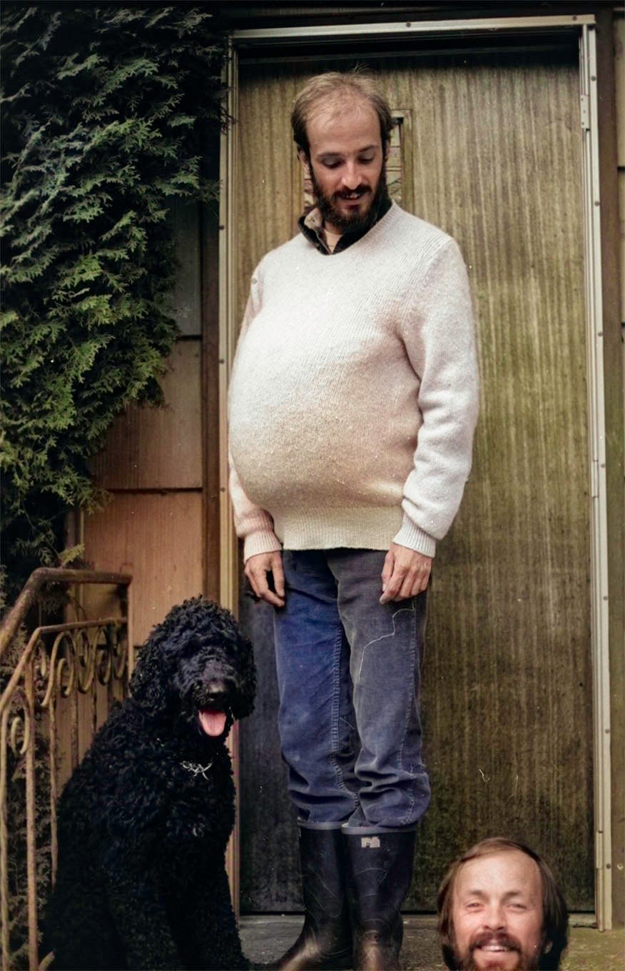 a man standing with a dog and another mans head below