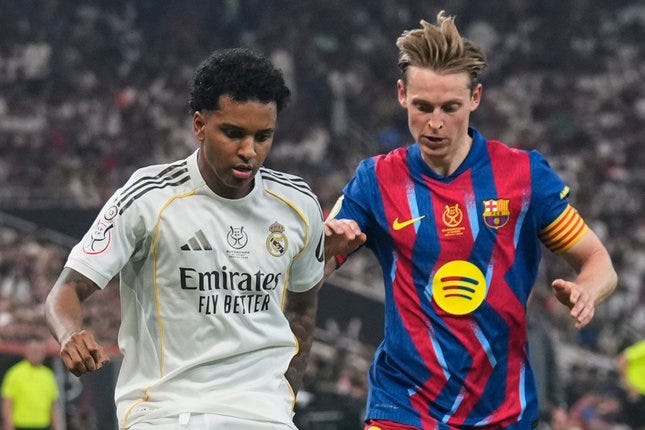Pemain Real Madrid Rodrygo (kiri) berebut bola dengan pemain Barcelona Frenkie de Jong pada laga final Piala Super Spanyol/Supercopa de Espana, Minggu, 11 Januari 2026 © AP Photo/Altaf Qadri