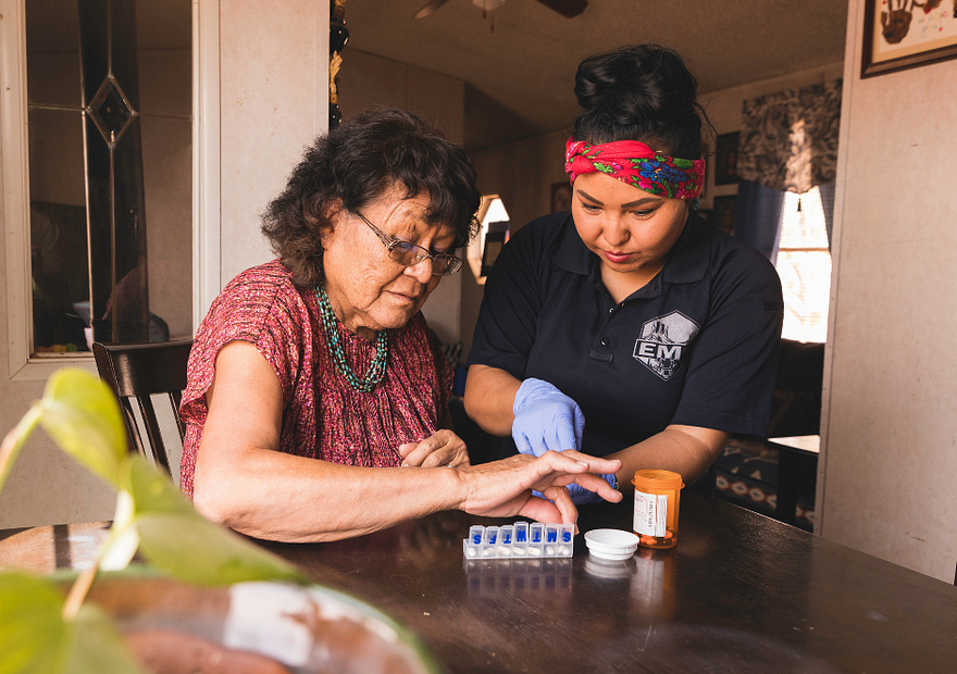Mujer tribal nativoamericana con una persona joven trabajando en seleccionar medicamentos en una mesa.