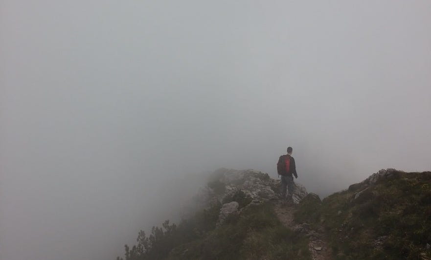 A person navigating a fogger mountain cliff, with uncertainty about what comes next