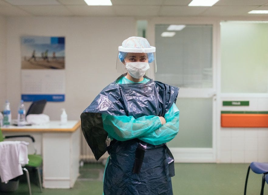 A health care professional wearing a trash bag for PPE.