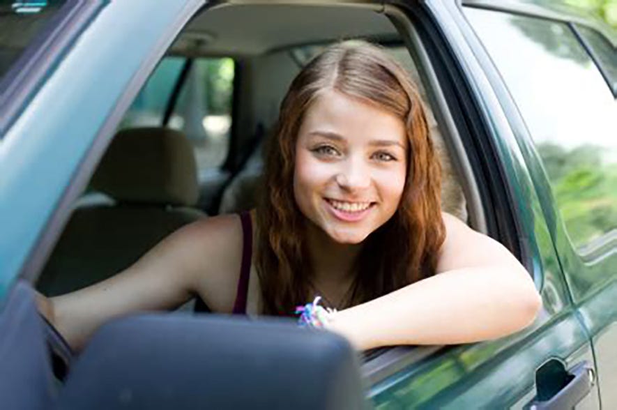 Pretty young girl smiling from driver’s die window.