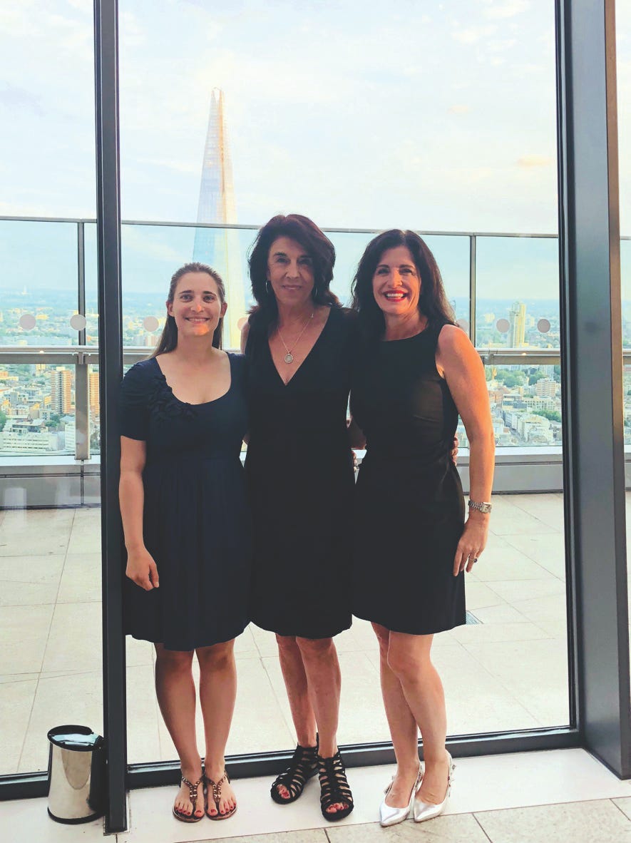 Kelley Steckelberg and two co-workers smile in an office in front of a large window