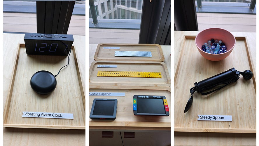 Some of the low tech / hardware available to try out, on top of a shelving unit — including a vibrating alarm clock, braille rulers and slates (to take notes), digital magnifiers and a steady spoon.