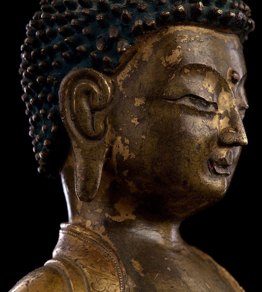 Buddhist Tibetan statue of man meditating with eyes half-open.