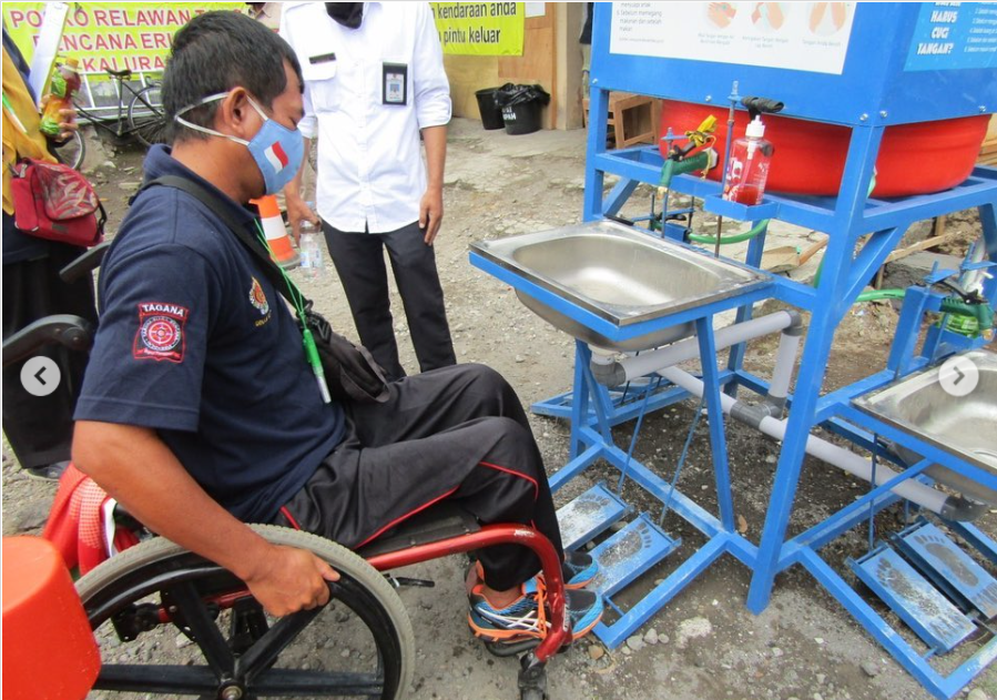 A man in a wheelchair testing an accessible handwashing station in Indonesia.