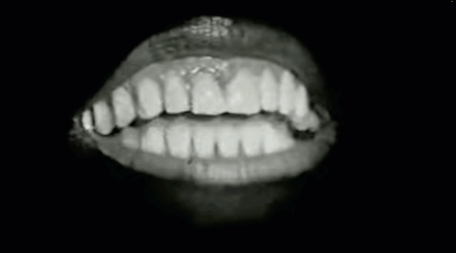A mouth with lips, teeth and tongue speaking dramatically against a black background