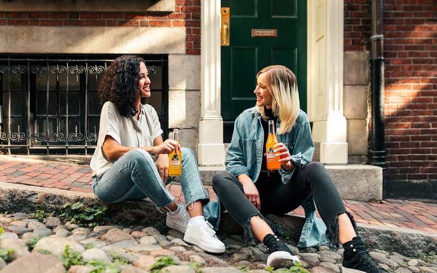 women sitting on the curb drinking juice