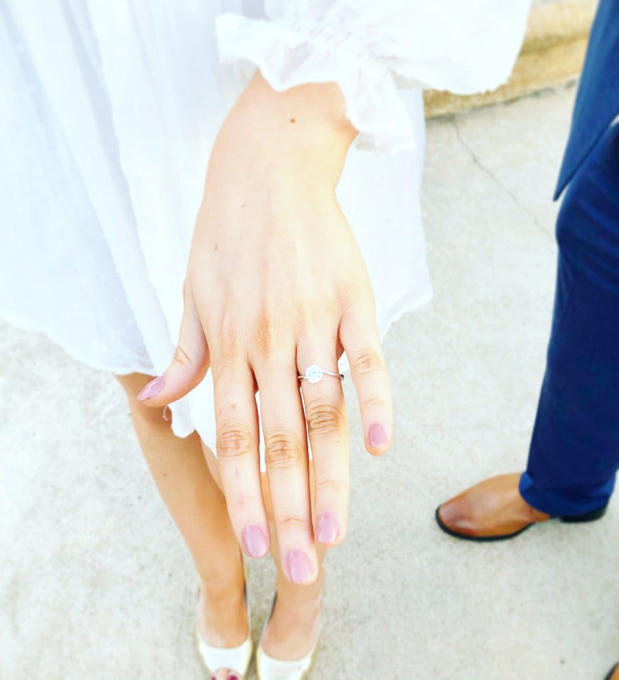 Girl in white dress showing off engagement ring
