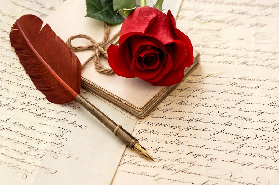 A red rose, small notebook and a red feather calligraphy pen on papers with paragraphs of fancy script.