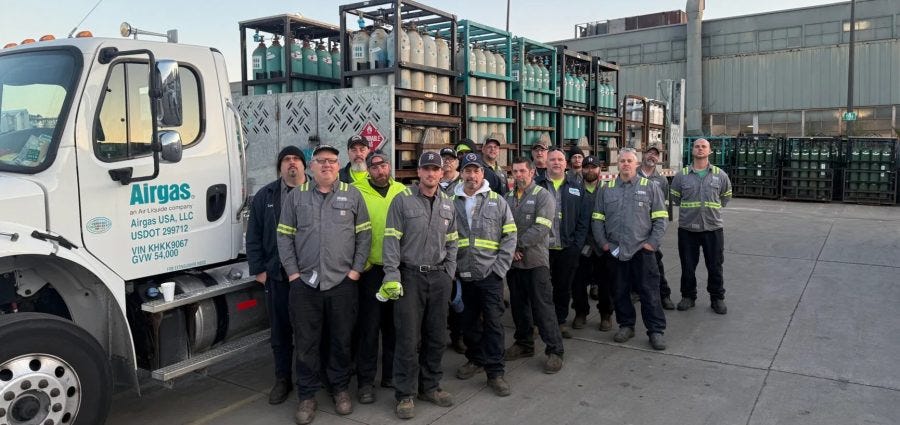 A group of Airgas workers poses in front of a truck full of product.
