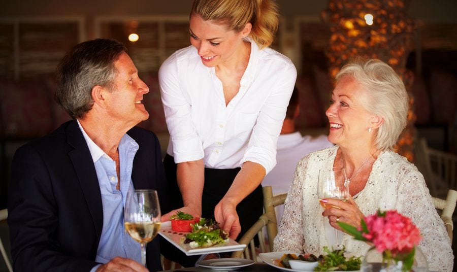 Waiter serving a happy couple at a restaurant