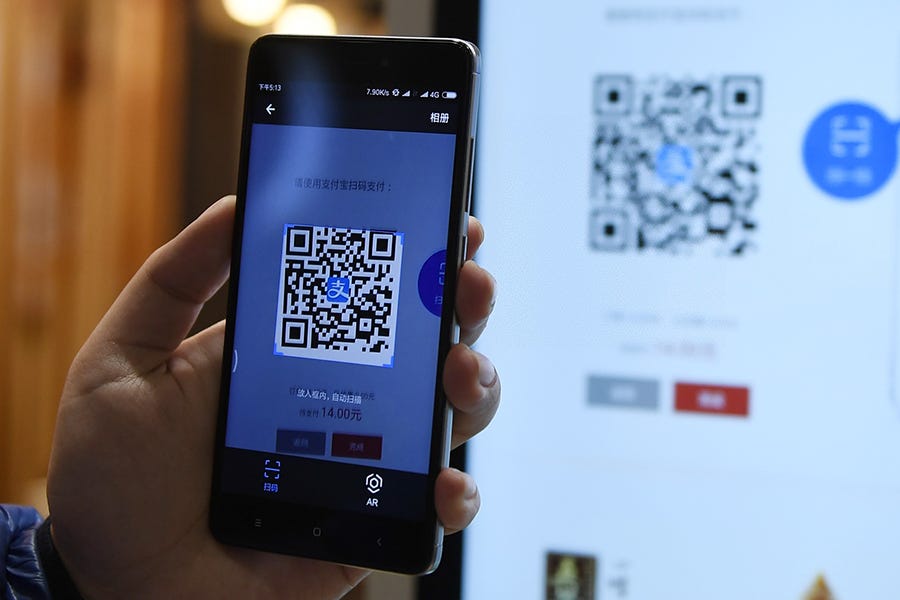 A phone being held up to a screen to scan a QR code.