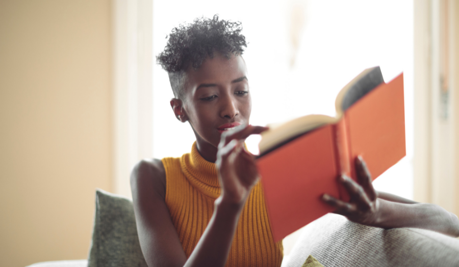 A young African woman reading a book at home
