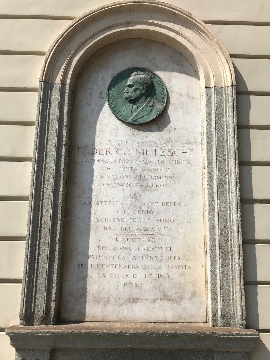 A plaque featuring a portrait of Friedrich Nietzsche with an inscription. This was placed outside his lodgings in Turin.