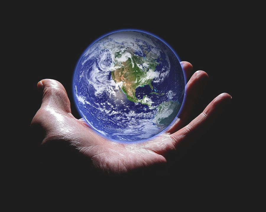 Hand holding a glass globe of the earth.