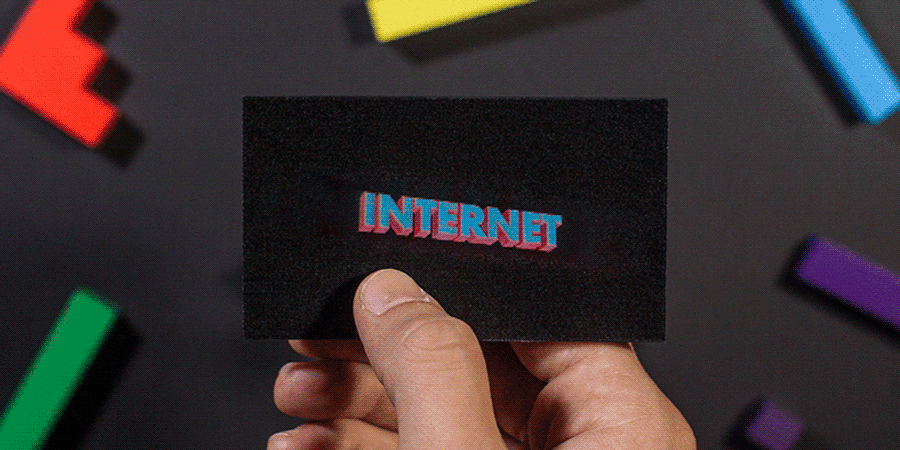 A hand holding a holographic business card with a GIPHY logo, moving slightly against a background of random colored blocks that are blurred.
