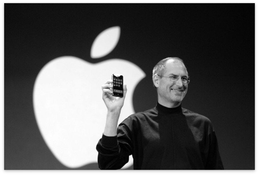 Steve Jobs holding up the original iPhone