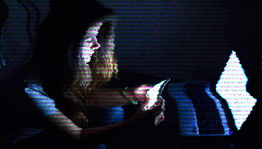 Woman sits in dark on laptop and mobile phone — distorted image