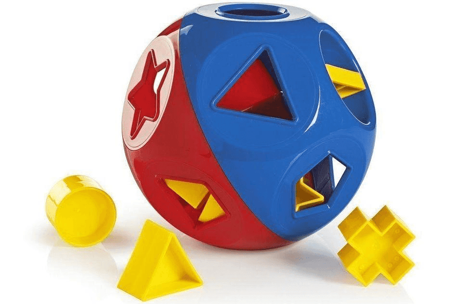 a child’s shape-sorter toy, roughly spherical, contains various shaped holes, that matching pieces scattered on the floor can fit into.