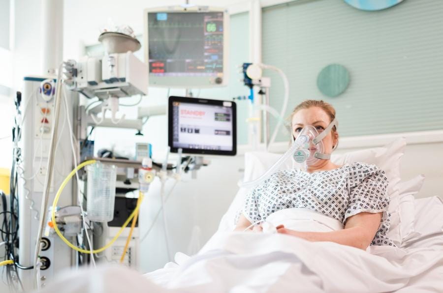 picture of a patient in a intentive care unit, next to a Mercedes AMG ventilator prototype