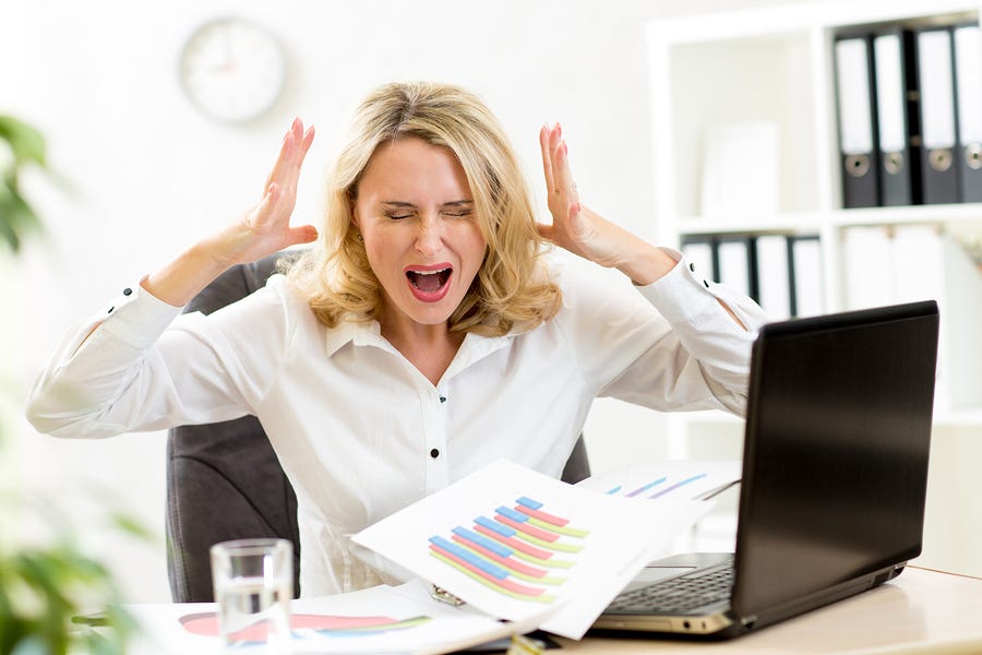 Photo of a female executive expressing frustration with laptop open