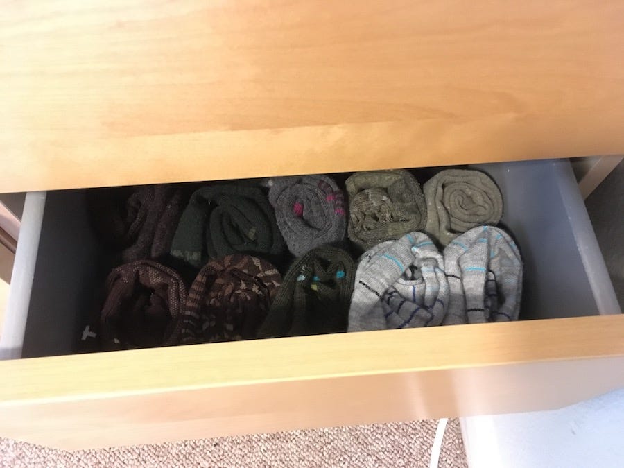 A drawer holding rows of neatly rolled socks, which are held in place in a hidden paper tray.