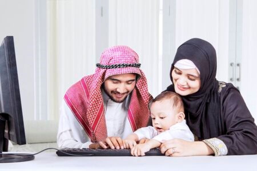 A mother and father attentively take care of their only child, sitting together at a table filled with toys and educational materials