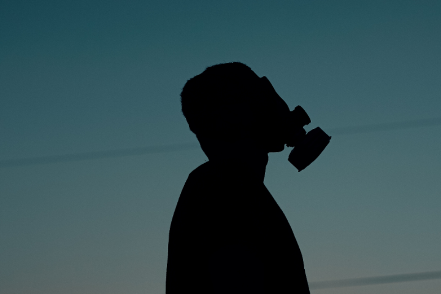A silhouette of a man in a gas mask against a dusk sky