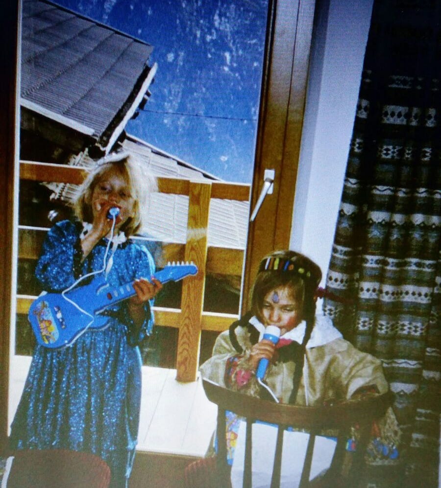Me as a child performing with a plastic guitar and microphone together with my sister.