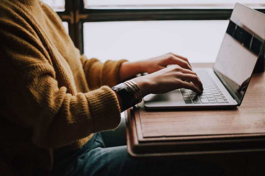 A person sitting down typing on a laptop