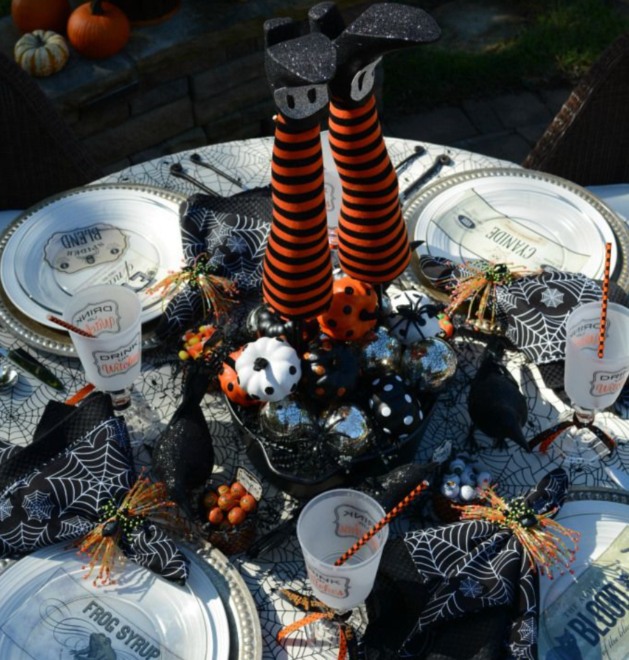 Halloween table setting with centerpiece featuring witches legs sticking up.