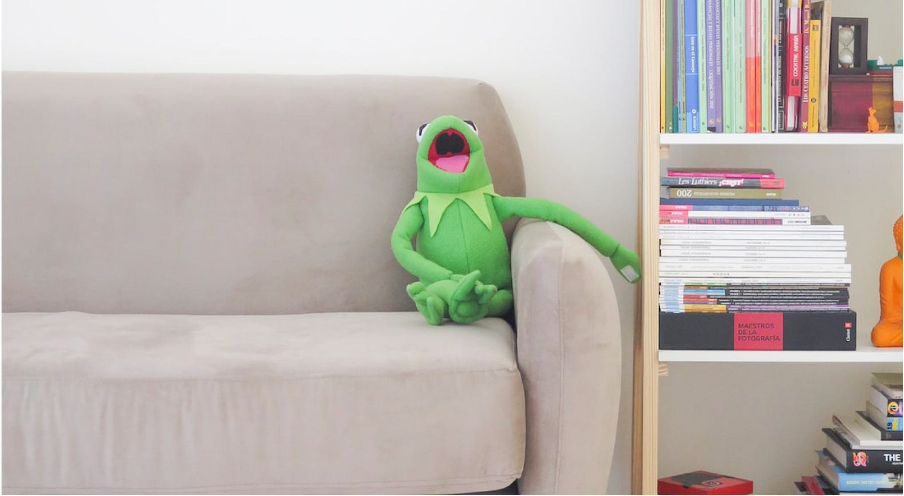 A toy frog laughing sitting on a sofa