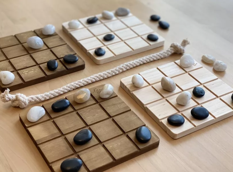 Example game of Shōbu. There are four 4x4 boards, two with a dark wood on the left and two with a light wood on the right. These boards have a small rope between them in such a way that each side has one dark and one light board. Boards are covered with black and white stones, each color under control by one player.