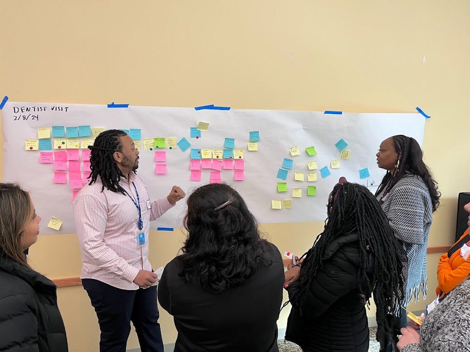 County government employees look at a board covered in sticky notes.