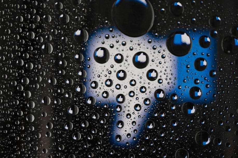 Water droplets on a glass panel offering a blurred vision of a thumbs-down