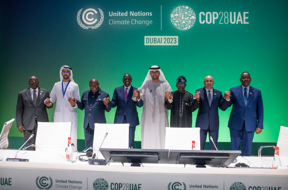 COP28 leaders standing in front of COP signage holding hands