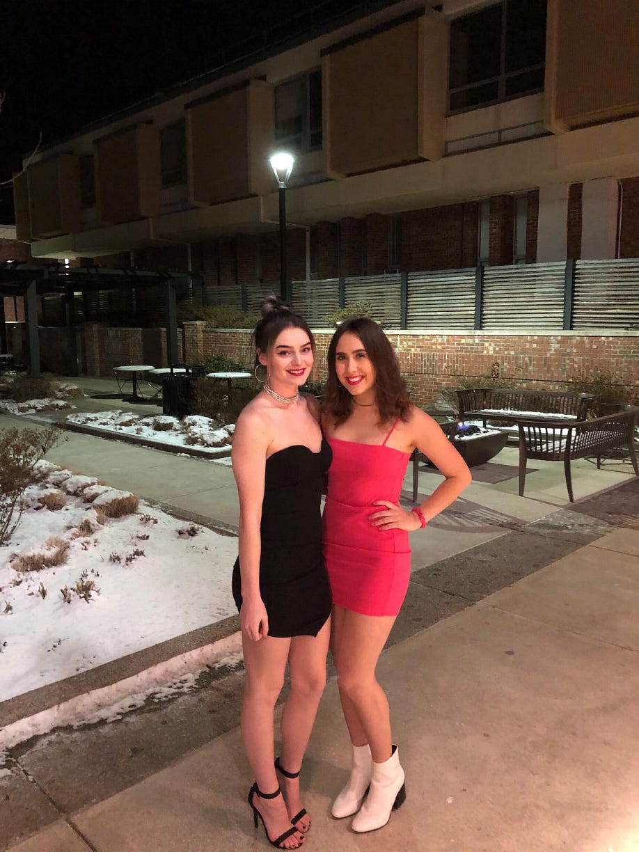 Myself wearing a hot pink mini dress with white ankle boots, and my friend next to me wearing a sleeveless black dress.