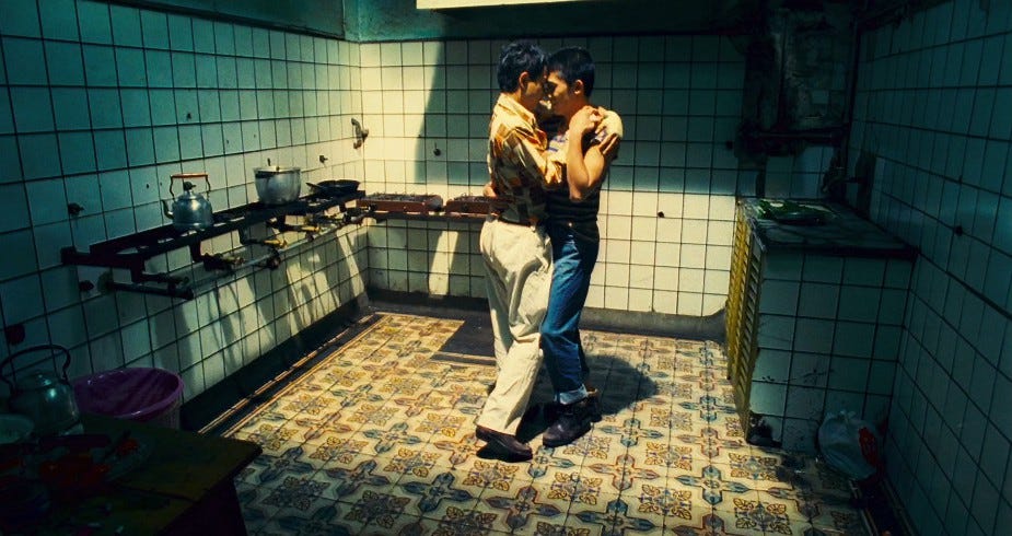 Dois homens dançando em uma cozinha.