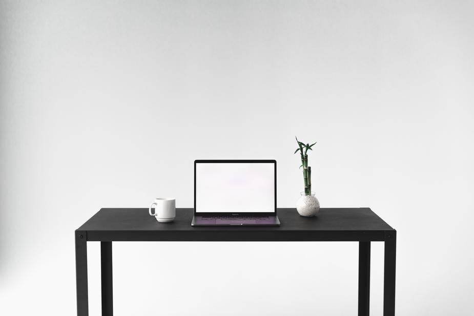 Minimalist desk space with a laptop, mug, and plant