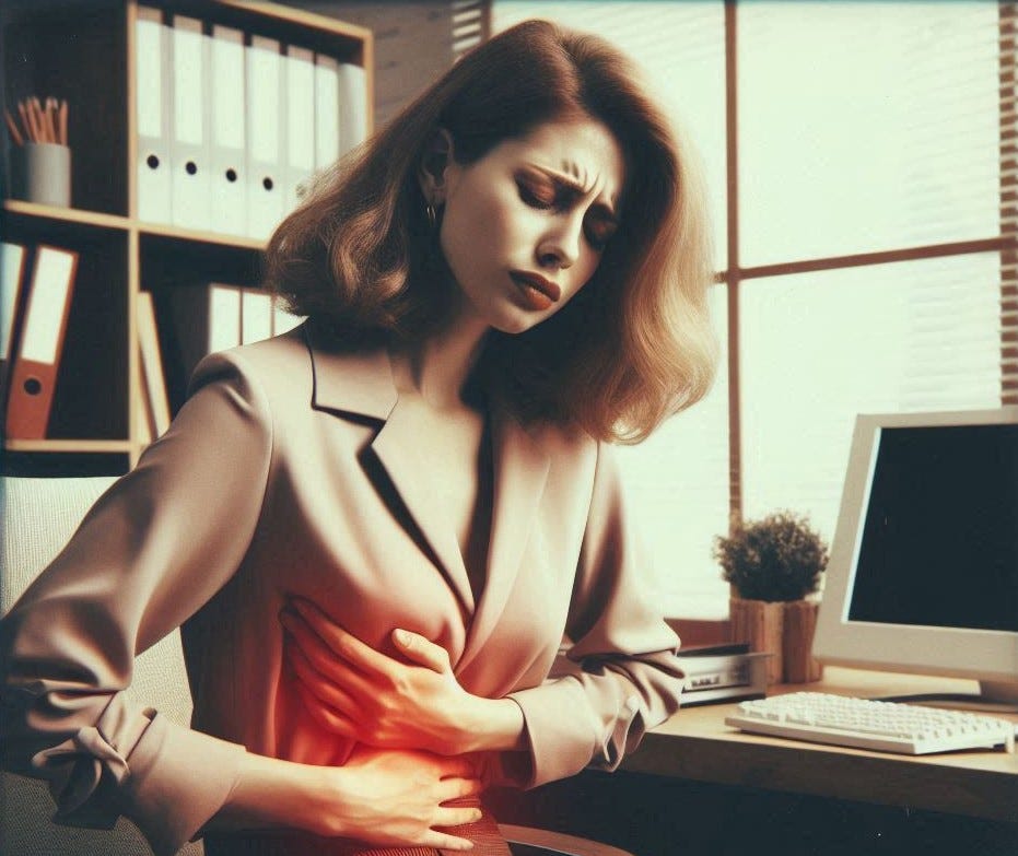 Vrouw met los donkerblond haar zit achter haar bureau in haar kantoor en heeft last van een vervette lever stress gerelateerd.