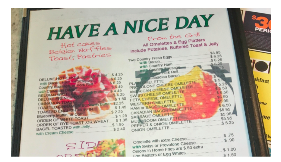 Image of a laminated menu with items printed on top of background images of food. The background images make it hard to distinguish the words.