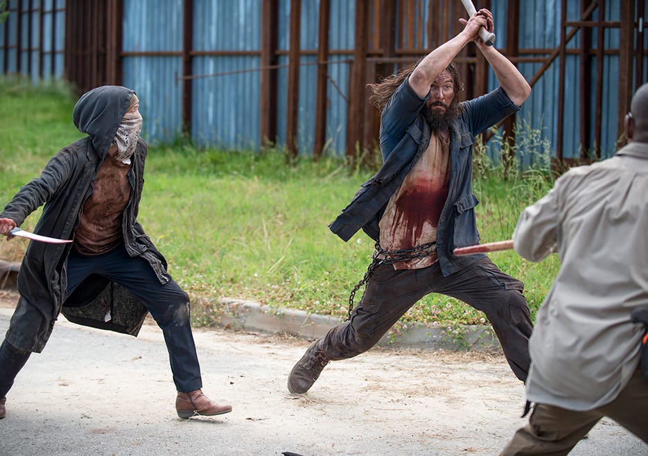 Carol dressed as a raider preparing to kill one of the attacking raiders with a knife.