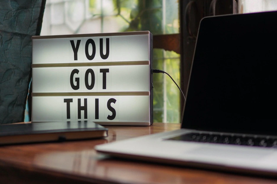 light up sign with block letters saying “you got this” next to computer