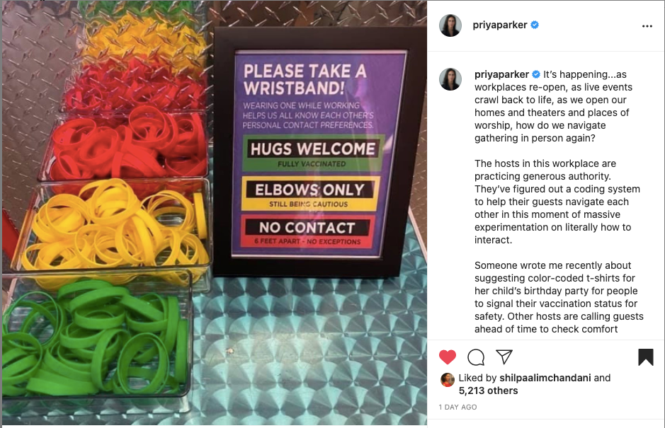 Photo of a table with red, yellow, and green bracelets sorted in three separate containers. A sign reads that green bracelets indicate hugs are welcome, yellow means elbows only and red means no contact.