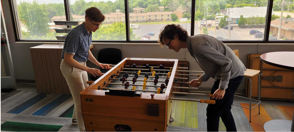 Two students playing at a foosball table