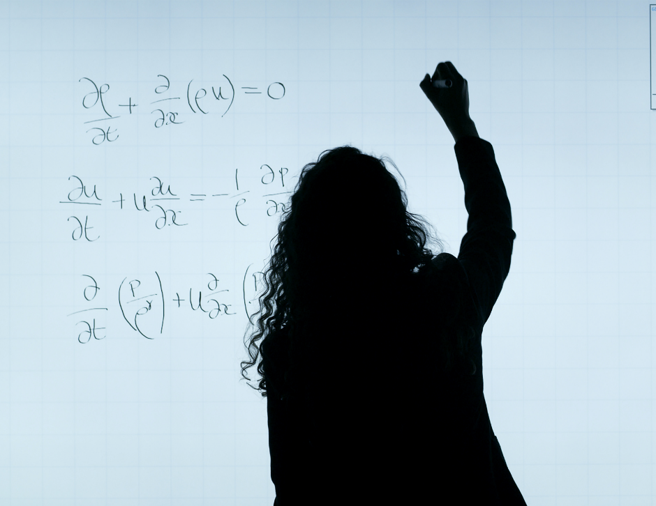 A silhouette of a person writing maths formulae on a white board